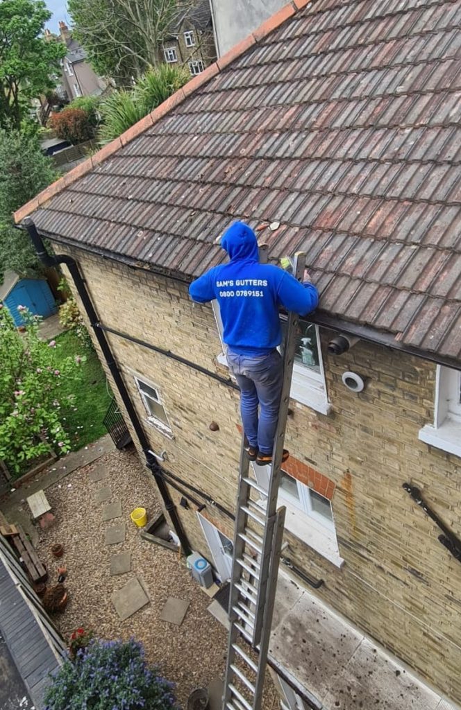 Man at height clearing gutter